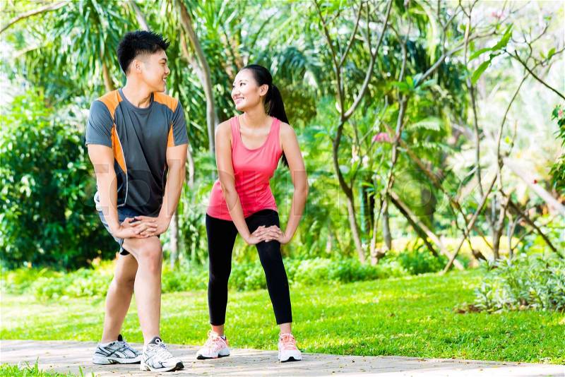 Asian Chinese man and woman stretching muscles in park for sport fitness, stock photo