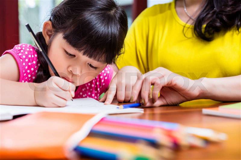 Chinese mother homeschooling her child teaching her daughter to write, stock photo