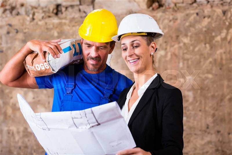 Architect and construction worker on site with plan or blueprint, stock photo