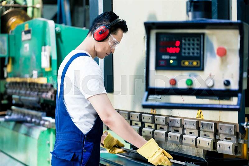 Asian machine operator in production plant checking data , stock photo