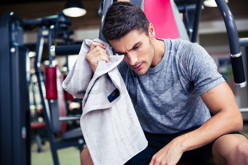 Portrait of a handsome bodybuilder wipes the sweat at fitness gym, stock photo