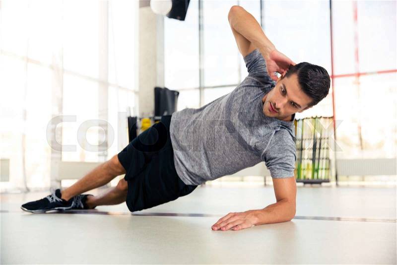 Portrait of a handsome man doing side plank at gym, stock photo