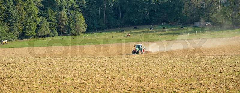 Agricultural scenery includig a a field and tractor in sunny ambiance, stock photo