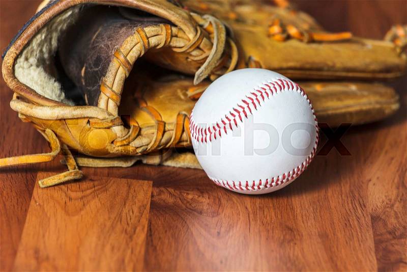 Baseball ball and baseball glove on wood background, stock photo