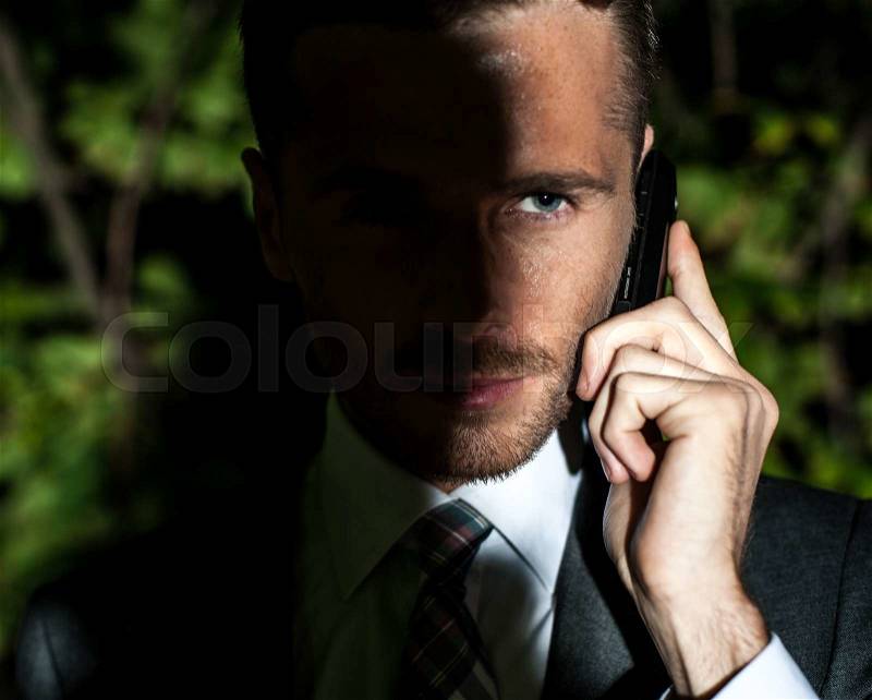 Portrait of handsome bearded man in classical elegant suit poses on street at night.Businessman speaks phone.Fashion look, stock photo