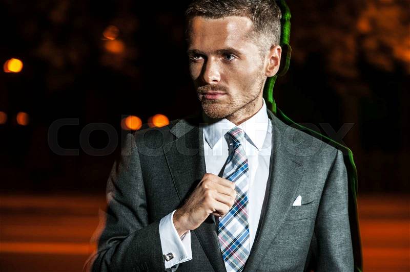 Portrait of handsome bearded man in classical elegant suit poses on street at night. Fashion look, stock photo