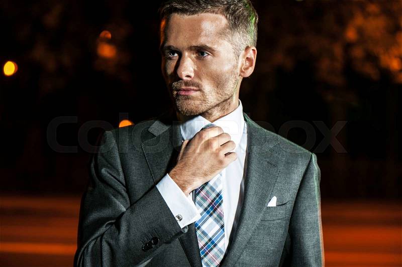 Portrait of handsome bearded man in classical elegant suit poses on street at night.Fashion look, stock photo