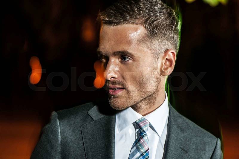 Portrait of handsome bearded man in classical elegant suit poses on street at night.Fashion look, stock photo