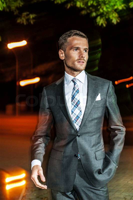 Handsome bearded man in classical elegant suit poses on street at night.Fashion look, stock photo