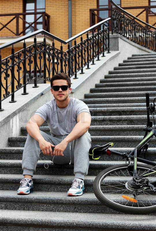Handsome young guy in sunglasses listens music near bicycle.Lifestyle.Sports man, stock photo