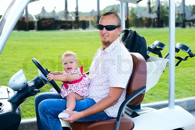 Dad and his little daughters driving golf cart, stock photo