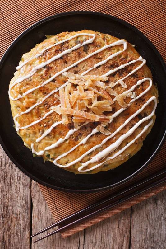 Japanese okonomiyaki on a table close-up and chopsticks. vertical top view\, stock photo