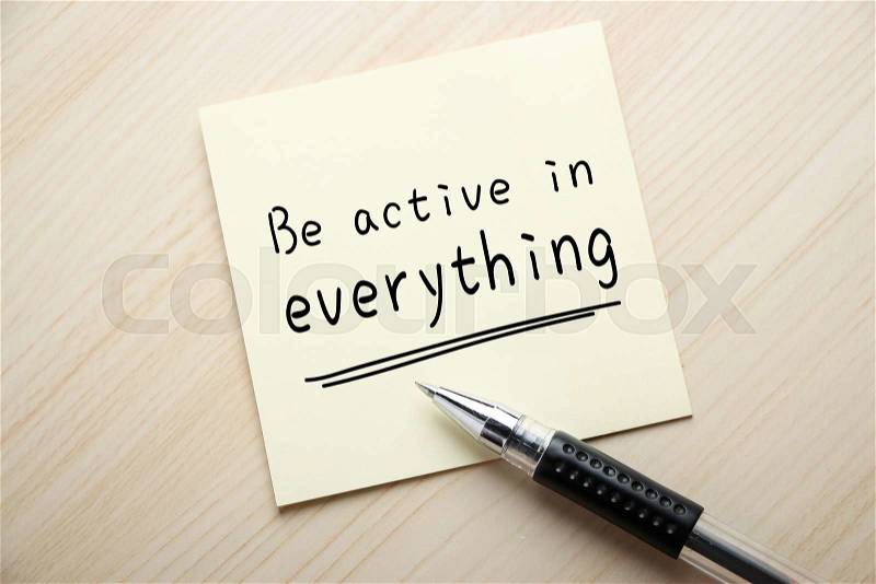 Text Be Active in Everything is written on the sticky note with ball pen aside, stock photo