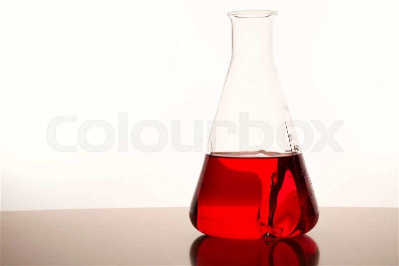 Measuring glass with red liquid on a table of a chemical laboratory, stock photo