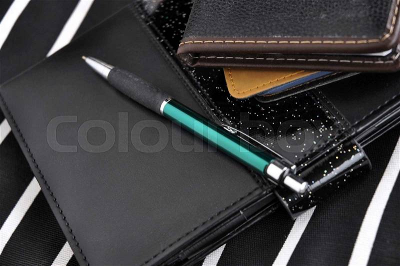 Pen put on black note book with stripes background, stock photo