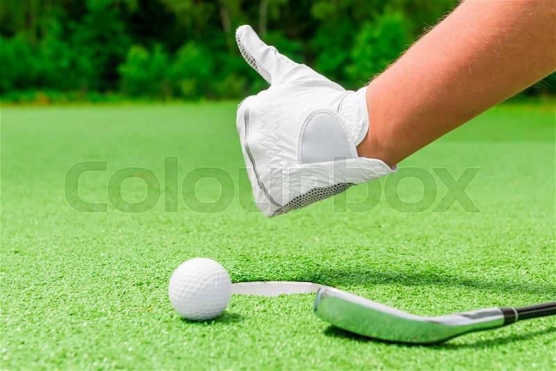 Closeup hand in a white glove and a ball near the hole, stock photo