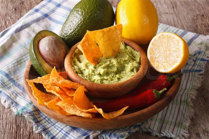 Mexican cuisine: nachos and guacamole sauce and ingredients close-up on the table. horizontal , stock photo