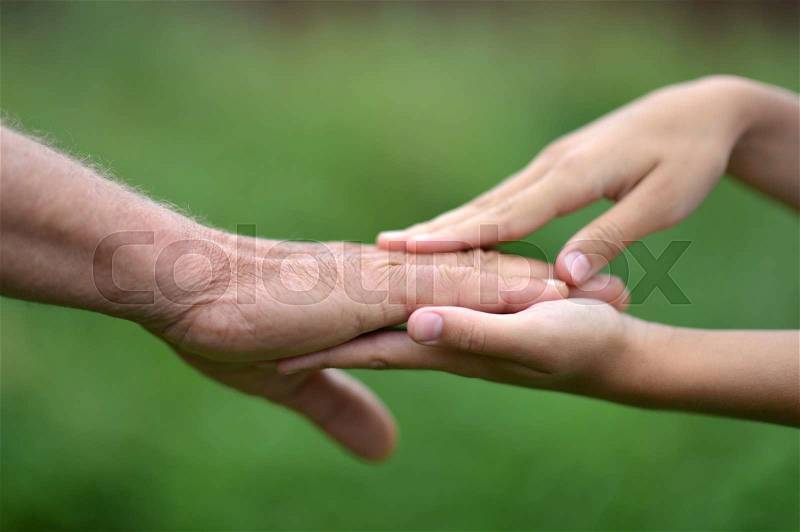 Two hands together against the green natural background, stock photo