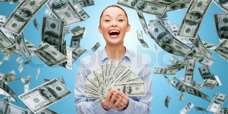 Business, money, finance, people and banking concept - happy laughing businesswoman with heap of dollar cash money over blue background, stock photo