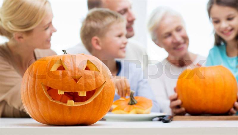 Generation, holidays and people concept - helloween pumpkin lantern over happy family at home, stock photo