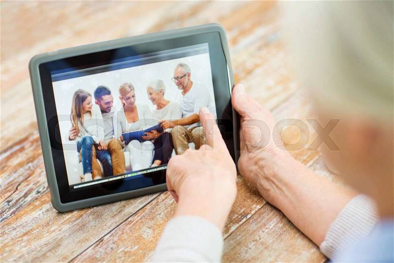 Technology, age, memories and people concept - happy senior woman with tablet pc computer viewing family photo album at home, stock photo