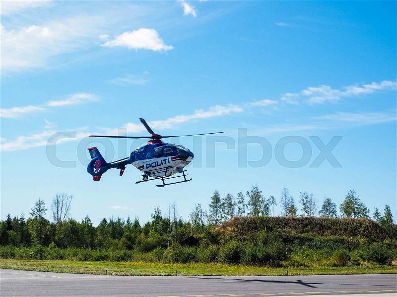 Police helicopter from norwegian authorities hoovering over landing field, stock photo
