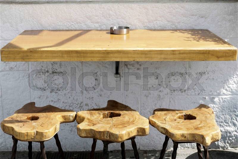 Bar table with three wooden stools and white wall, stock photo