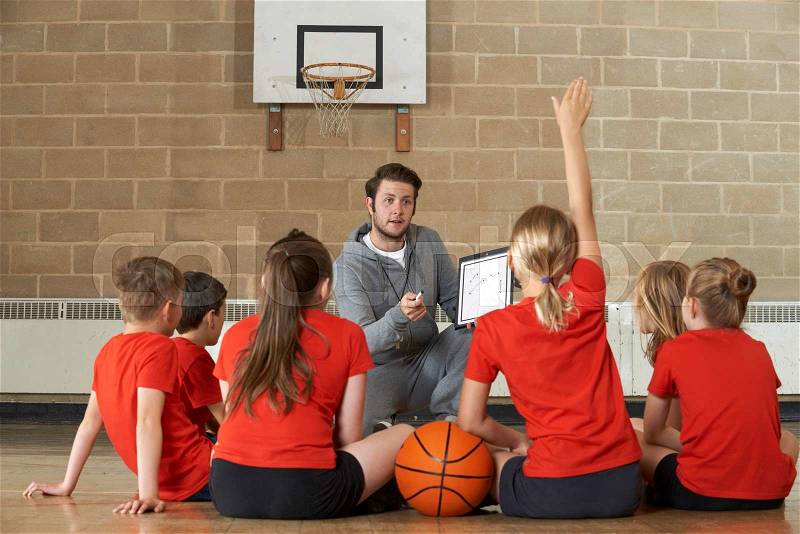 Coach Giving Team Talk To Elementary School Basketball Team, stock photo