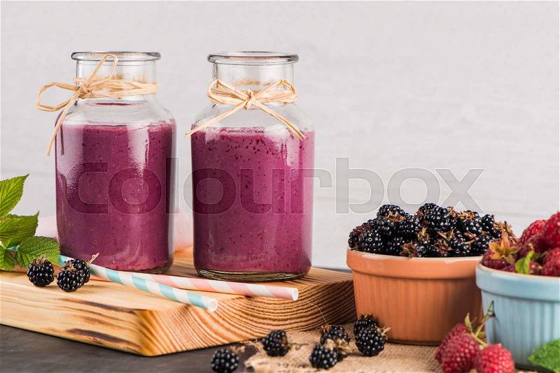 Fresh red fruits smoothie on vintage decorated wooden table, stock photo