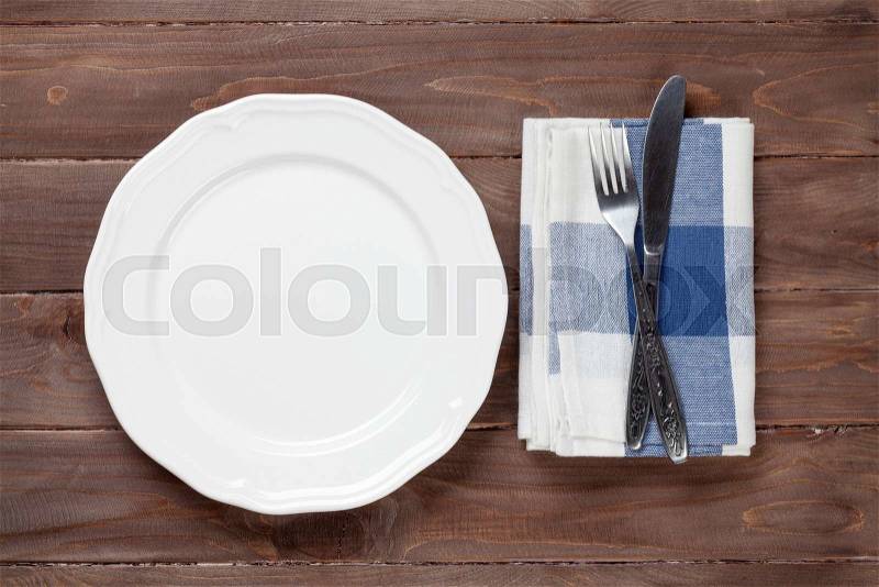 Empty plate and silverware over wooden table background. View from above with copy space, stock photo