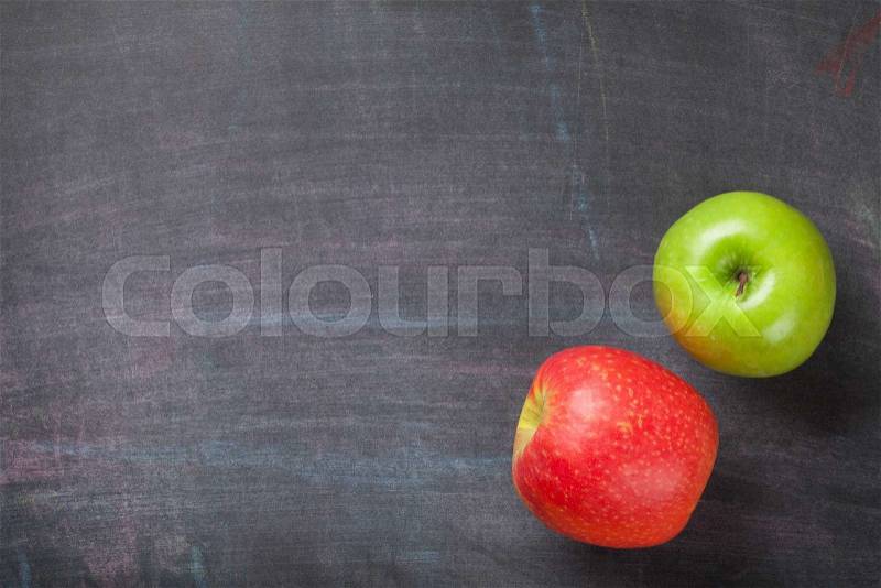 Green and red apples on blackboard or chalkboard background. Top view with copy space, stock photo
