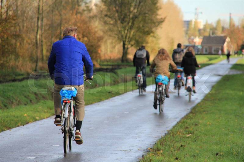 The man is going to his work and in the distance the students going to school at the bike at the cycle path in fall, stock photo
