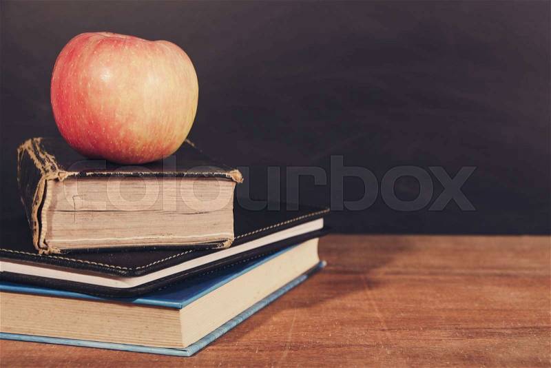 Apple and Books on the wooden desk with Blackboard Background, stock photo
