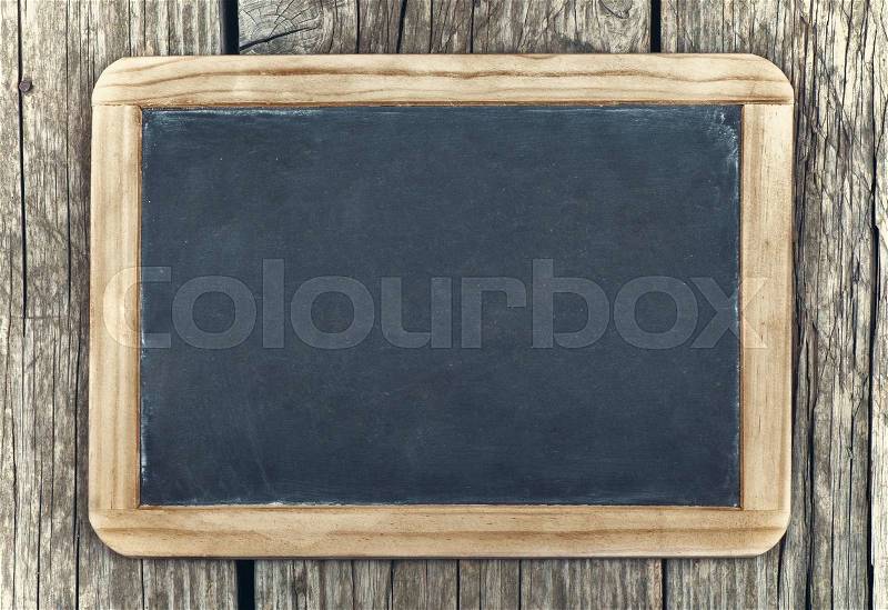 Empty vintage blackboard with wooden frame on a wooden background, stock photo