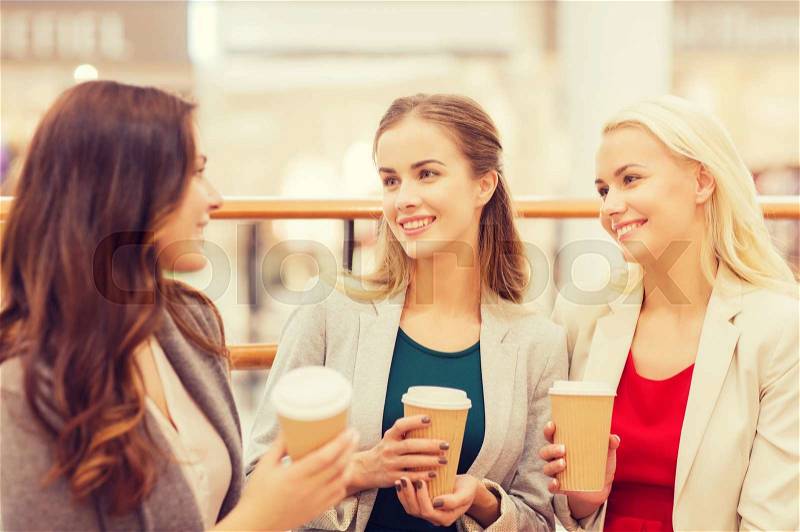 Sale, consumerism and people concept - happy young women with shopping bags and coffee paper cups in mall, stock photo