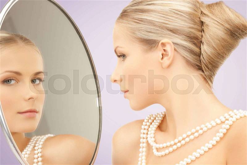 Beauty, luxury, people, holidays and jewelry concept - beautiful woman with sea pearls beads or necklace looking to mirror over violet background, stock photo