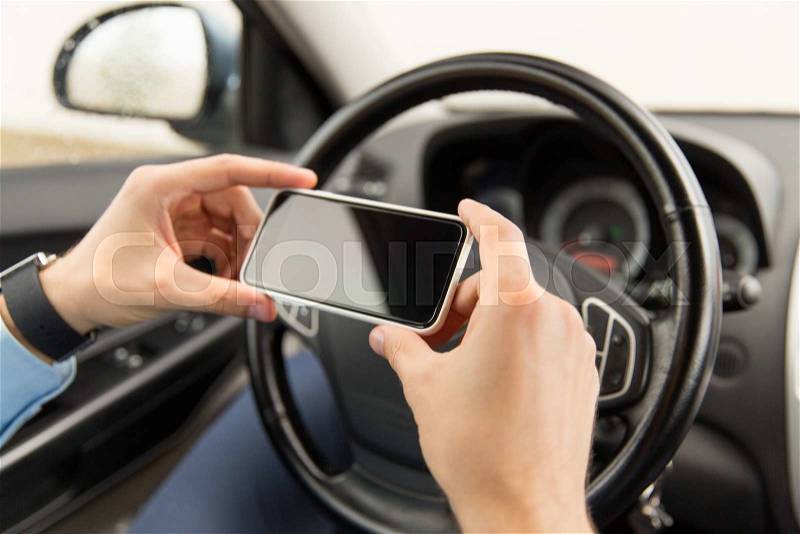 Transport, business trip, technology and people concept - close up of young man hand with smartphone driving car, stock photo
