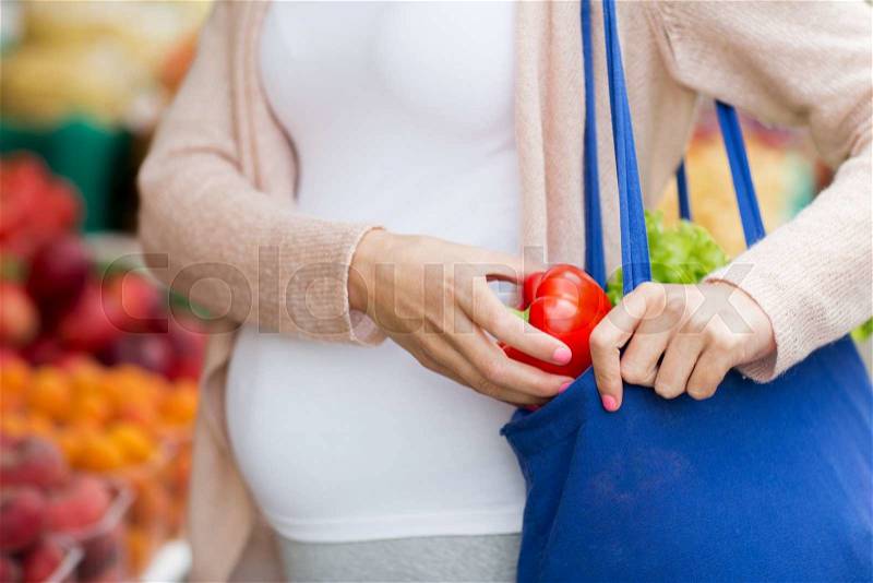 Sale, shopping, food, pregnancy and people concept - close up of pregnant woman buying red pepper or paprika at street market, stock photo