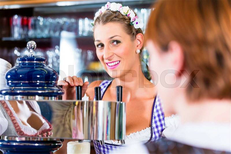 Innkeeper in Bavarian pub with customers, stock photo
