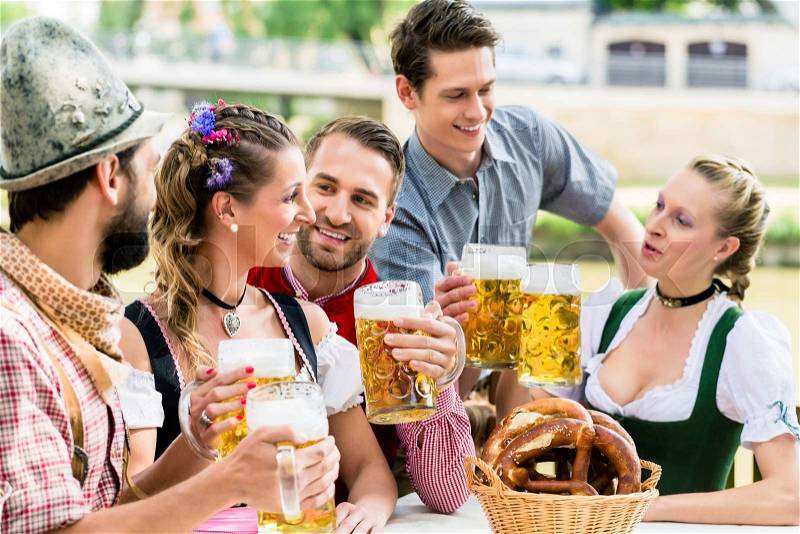 Friends in Bavarian beer garden drinking in summer, stock photo