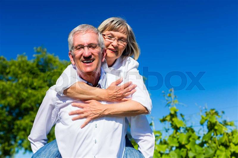 Senior woman hugging her man from behind, stock photo