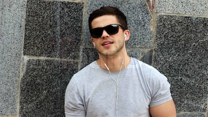 Handsome young guy in sunglasses listens music near bicycle.Lifestyle.Sports man, stock photo