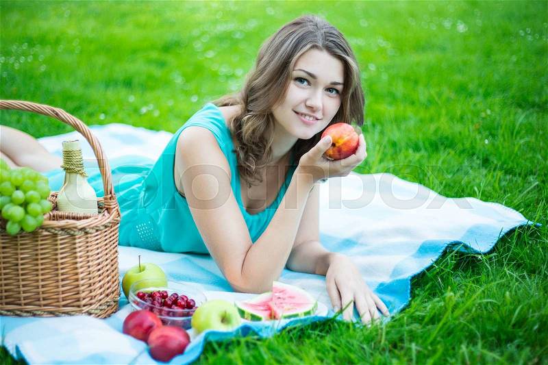 Beautiful woman with picnic basket and fruits in summer garden, stock photo