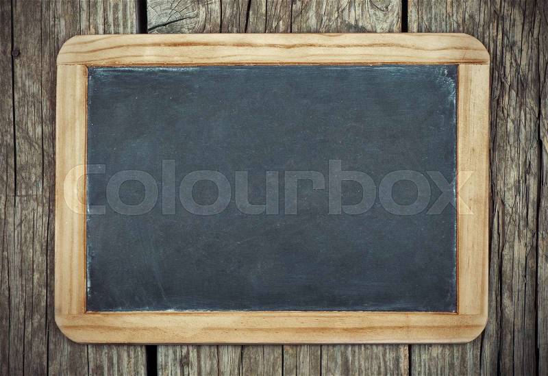 Empty vintage blackboard with wooden frame on a wooden background, stock photo