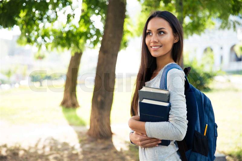 Portrait of a smiling female student walking outdoors, stock photo