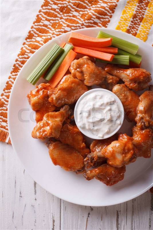 Buffalo wings with cheese sauce and celery on the table close-up. vertical top view\, stock photo