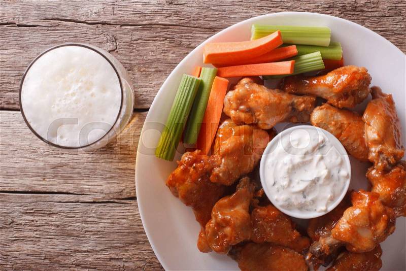 American fast food: buffalo wings with sauce and beer on the table close-up. horizontal view from above , stock photo