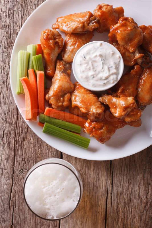 American fast food: buffalo wings with sauce and beer on the table close-up vertical view from above\, stock photo