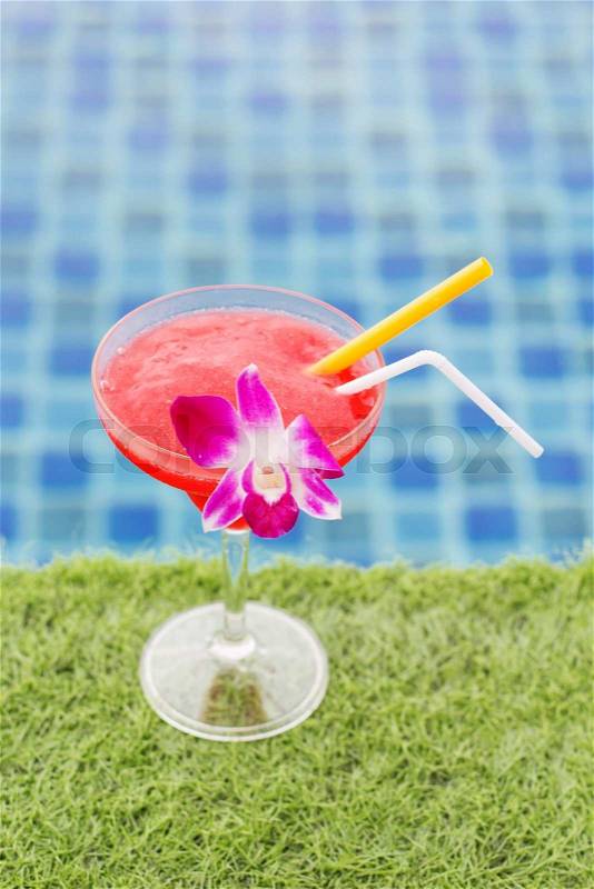 Frozen margarita with strawberry on grass near swimming pool, stock photo