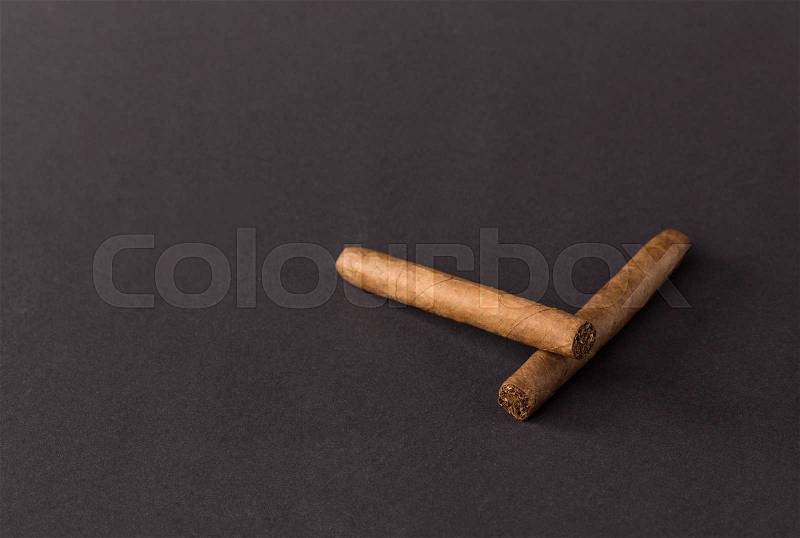 Two fine cigars. Located on a black background, stock photo